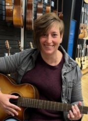 Angie Morris playing an acoustic guitar in a music store.