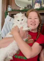 Woman holding a white cat, smiling.